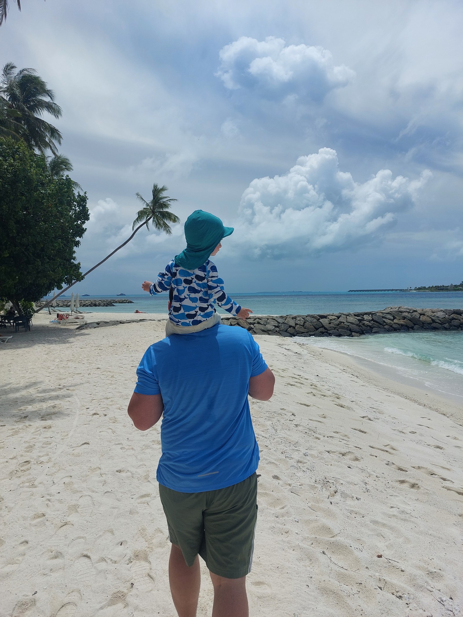 Papa trägt Lolo auf den Schultern am Strand der Malediven