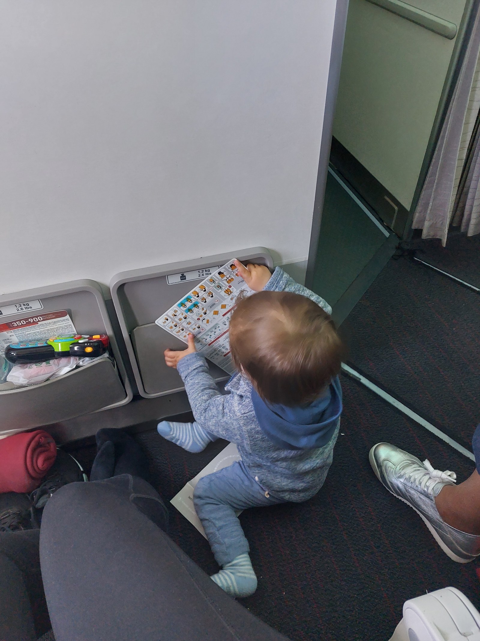 Lolo spielt auf dem Boden im Flugzeug mit der Sicherheitskarte