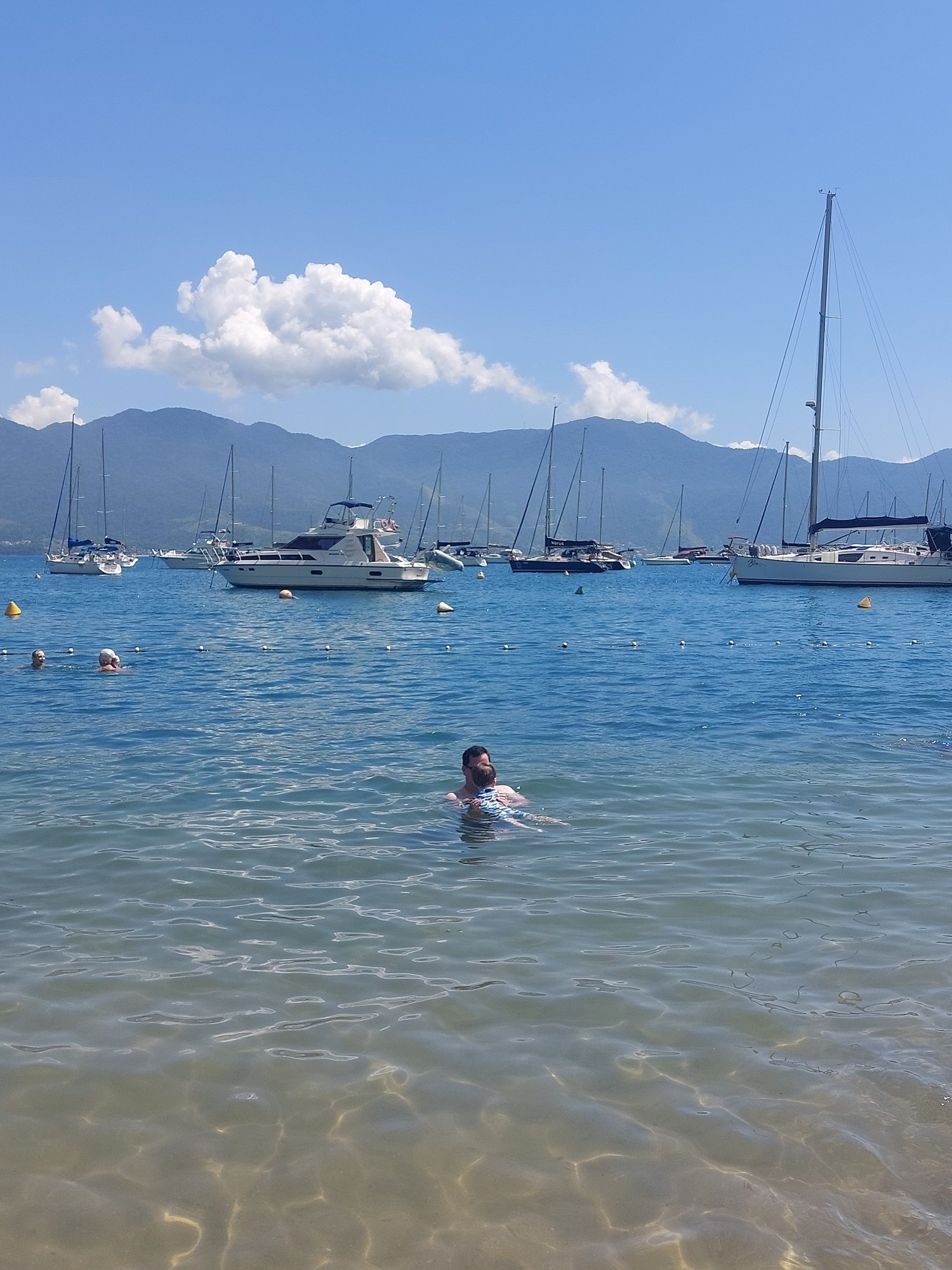 Papa und Lolo schwimmen gemeinsam im Wasser in Ilhabela