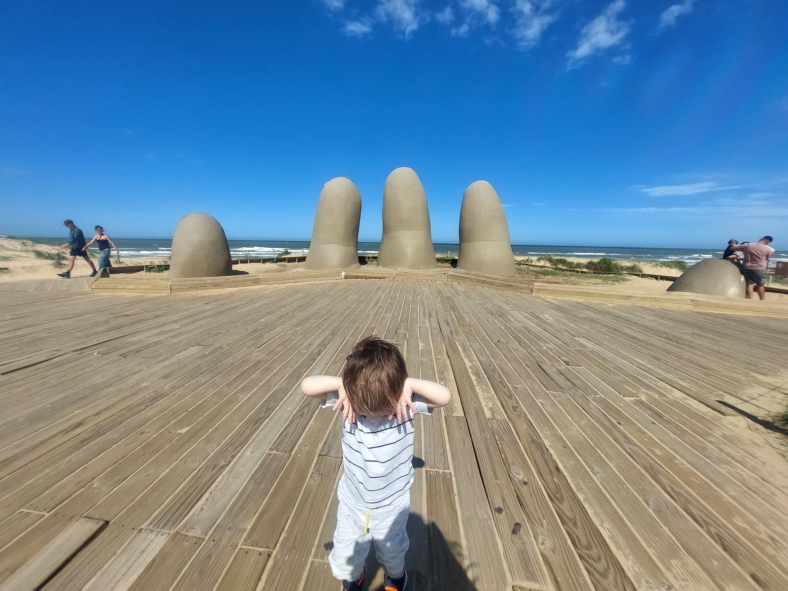 Lolo sitzt im Sand vor Los Dedos Punta del Este